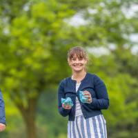 A woman stands smiling holding bags